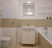 A bathroom in a 2-room apartment with a bathtub, sink, toilet, and washing machine.