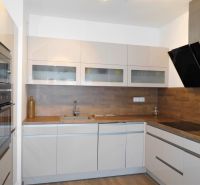 A kitchen in a 2-room apartment with white cabinets and a wood-patterned floor.