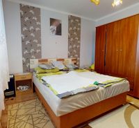 A bedroom in a 3-room apartment with floral wallpaper and a wooden decor floor.