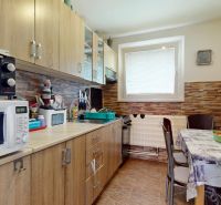 A kitchen in a 3-room apartment with a kitchen unit, microwave, and dining table.