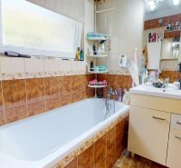 A bathroom with a shower, sink, and tiles in a 3-room apartment.