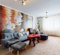 Living room in a 3-room apartment with a striking floral wallpaper and comfortable seating.