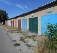 Garages on Ľudovíta Stárka Street in Trenčín with doors of various colors and trees.