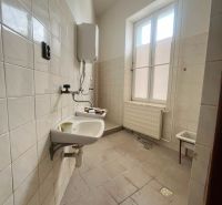 Bathroom in production premises with sinks and a boiler, tiled floor.