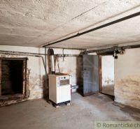Basement spaces with a boiler in a family house. The walls are damp and peeling.