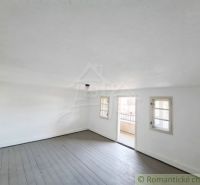 A spacious room with a wood-patterned floor in a family house with white walls.
