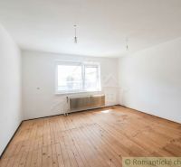 A room in a family house with a wooden decor floor and a window with a radiator.