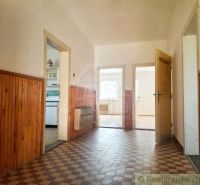 A hallway in a family house with paneling, tiles, and open doors to the rooms.