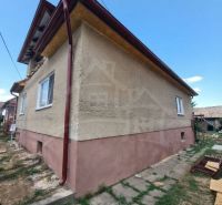 A family house in Ružiná with windows and a brown roof in a landscaped garden.