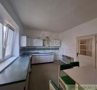 A kitchen in a family house with a dining table, white cabinets, and a large window.