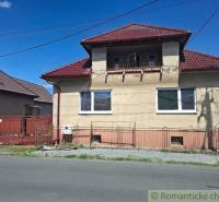 A family house in Ružiná with a brown roof and gate, next to the road.