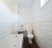 A bathroom in a family house with a bathtub, a sink, and a toilet, with light tiles.