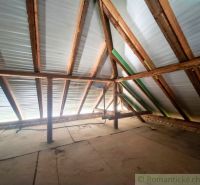 The attic of a family house with wooden beams and light penetrating through the roof.