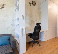 A workspace in a studio apartment with a wood-patterned floor and a decorative wall.