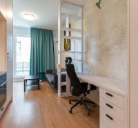 Interior of a 1-room apartment with a table, chair, and floor with wooden decor.