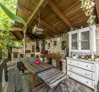 Rustic terrace with wooden furniture and a tiled stove in a family house.