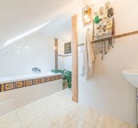 A bathroom in a family house with a bathtub, tiles with ornaments, and a jewelry hanger.