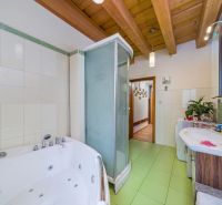 Bathroom with a bathtub, shower corner, and wooden ceiling in a family house.