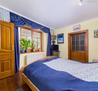 Bedroom with curtains, wooden doors, and a wooden decor floor in a family house.