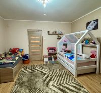 Children's room with wood-decor flooring, beds, and toys in a family house.