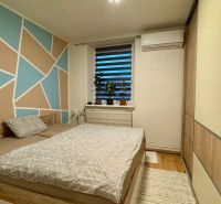 Bedroom in a family house with a colored wall and a bed, floor with a wooden decor.