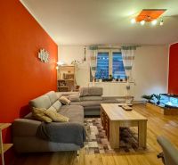 Living room of a family house with red walls, a sofa, and a wooden decor floor.