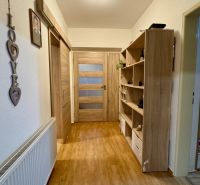 A hallway with a wooden decor floor, shelves, and decorations in a family house.