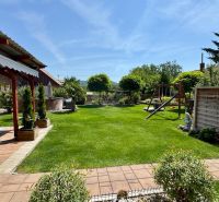 The garden of a family house in Čakajovce with a gazebo, lawn, and children's playground.