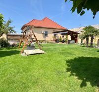 The garden of a family house in Čakajovce with a lawn, a gazebo, and a children's playground.