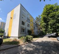 The exterior of the apartment building on Rákóczi Street in Komárno surrounded by trees and cars.