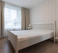 A bright bedroom with white furniture and a wood-patterned floor in a 2-room apartment.