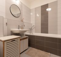 A bathroom with a bathtub and white tiles in a 2-room apartment, modern furnishings.