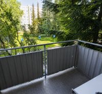 A balcony with a view of greenery, with residential buildings in the background, Žilina, Tulská 5.