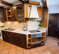 A kitchen in a 2-room apartment with dark wooden furniture and built-in appliances.
