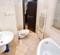A bathroom with a bathtub, sink, and toilet in a 2-room apartment with ceramic tiles.