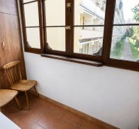 A balcony in a 2-room apartment with a wooden decor and a view of greenery.