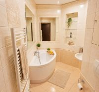 A bathroom with a bathtub and tiles in a 2-room apartment.