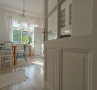 A bright dining room with white furniture and a wooden decor floor in a 4-room apartment.