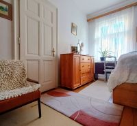 A room in a 4-room apartment with a carpet and furniture in wood decor.