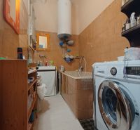 Bathroom of a 4-room apartment with a sink, washing machine, and hot water tank.