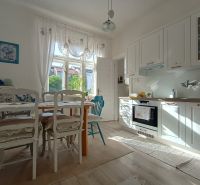 A kitchen in a 4-room apartment with white furniture and a floor with a wood decor.