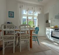 Bright kitchen in a 4-room apartment with white cabinets and decorative curtains, floor with wood decor.