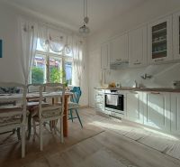 A bright kitchen in a 4-room apartment with white cabinets and a dining table.