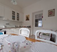 A kitchen in a 4-room apartment with light cabinets and wooden floor decor.
