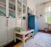 A view of a cozy interior of a 4-room apartment with white cabinets and a blue dresser.