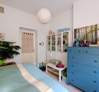 A bedroom with a green plant, a blue dresser, and a colorful bed in a four-room apartment.