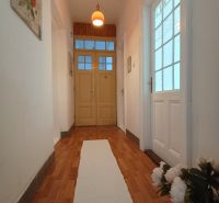 A hallway with bright lighting, a floor with a wooden decor, a simple white carpet.