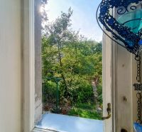 View from the window of a 4-room apartment onto a garden with lush greenery and decoration.
