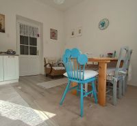 A bright dining room in a 4-room apartment with colorful chairs and decorations on the wall.