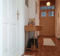 A hallway in a 4-room apartment with a wooden decor floor and a table.
